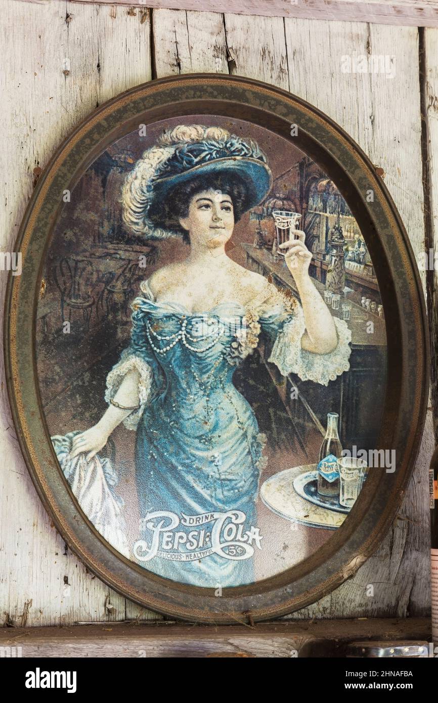 Pepsi Cola oval serving tray with silkscreen printed woman's portrait on wall inside old rustic wood plank cabin. Stock Photo