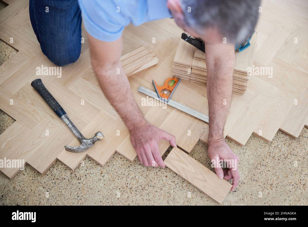 Overhead View Of Carpenter Or Builder Laying New Wood Block Parquet Parquet Floor In Kitchen At Home Stock Photo