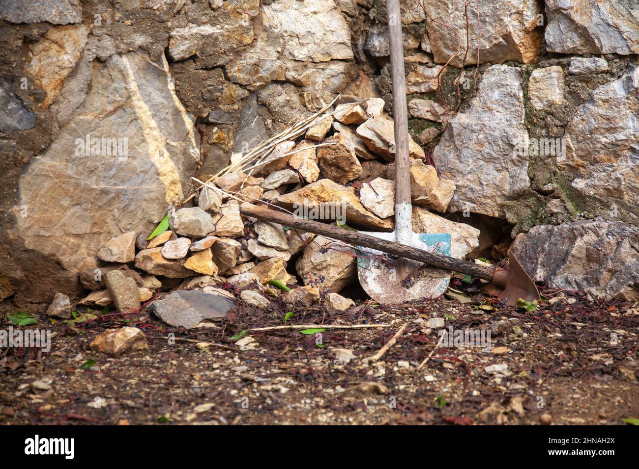 Garden corner. An old stone wall and an outdated garden shovel. Stock Photo