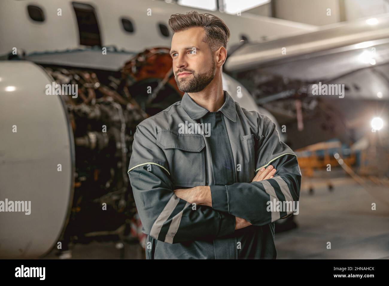 Bearded man aircraft maintenance engineer standing in hangar Stock Photo