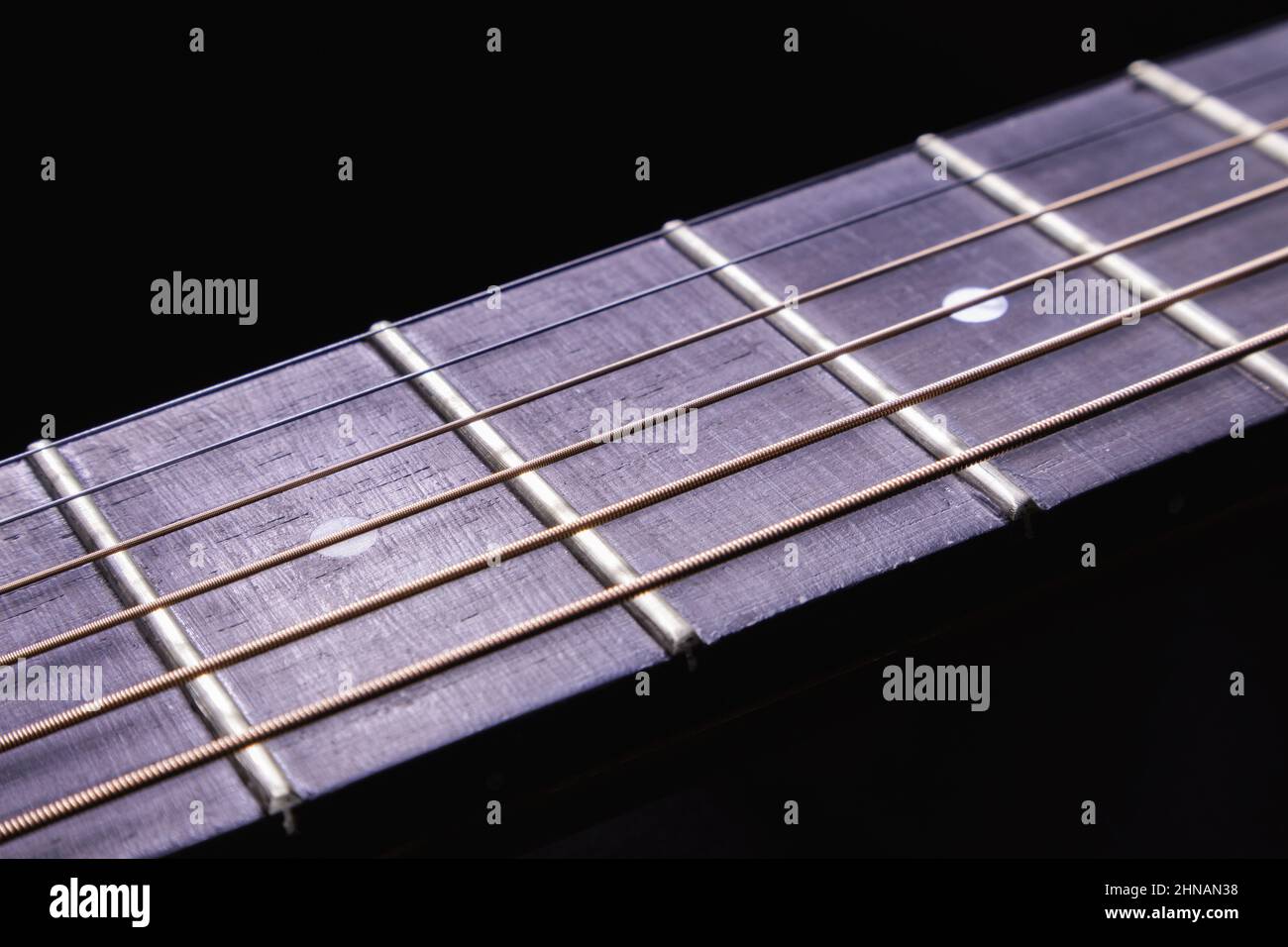 Details of an acoustic guitar neck and fretboard. Stock Photo