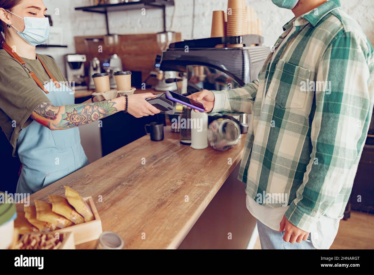 Man using smartphone to pay for coffee in cafeteria Stock Photo