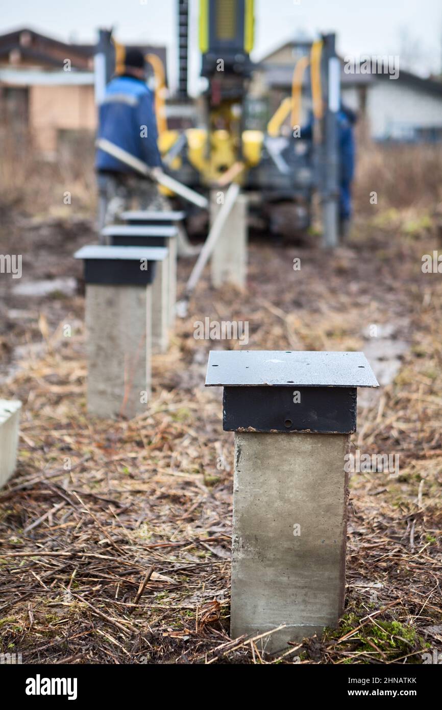 Concrete pile drilling with piling machine, foundation for wooden frame house, ground works Stock Photo