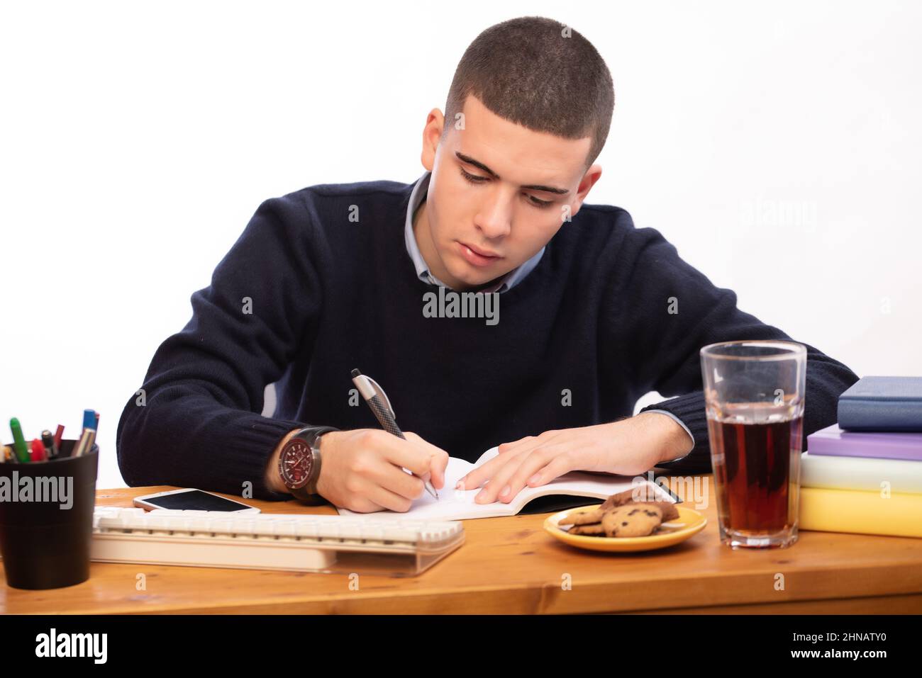 young men writing in a book and working in the computer at home, online ...