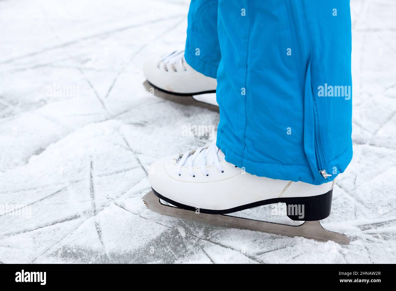 Female legs are in figure skates on a lake ice, close up view Stock Photo