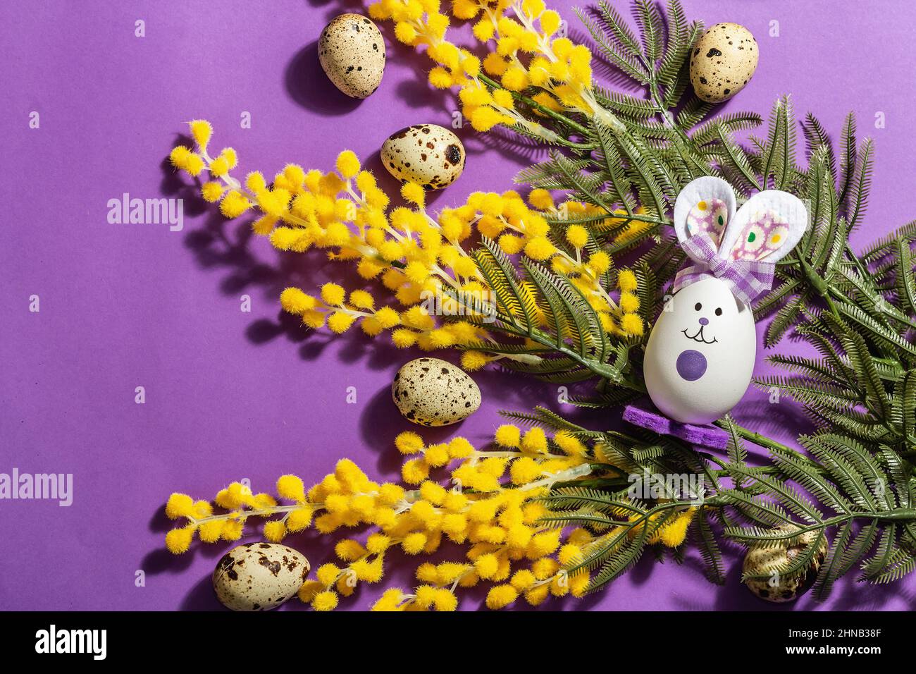 Spring composition with flowers, pastel eggs and cute rabbit on purple ...