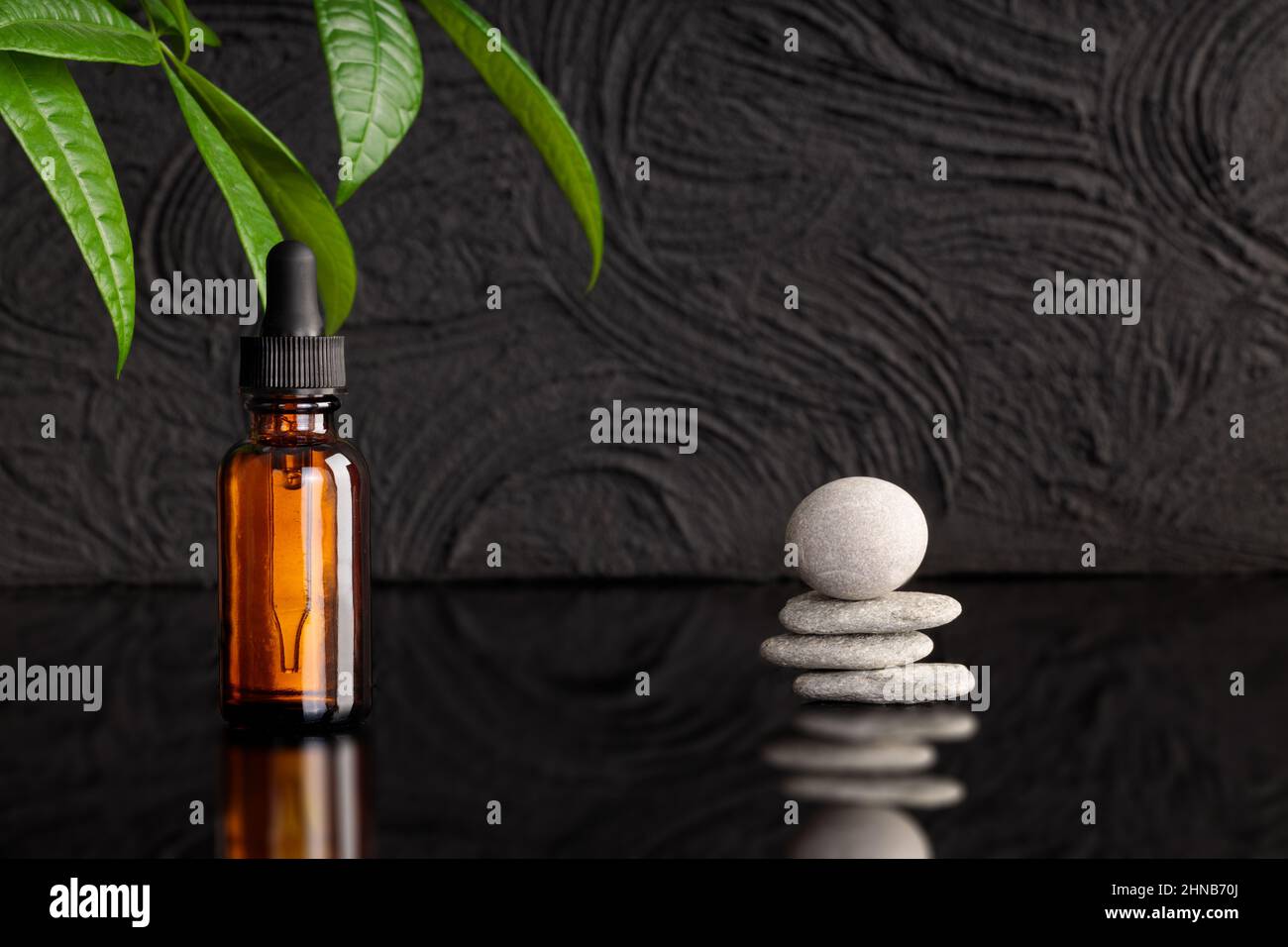 Pipette with oil, amber bottle on black background. Stone on stone, balance. Concept image, mockup. Stock Photo
