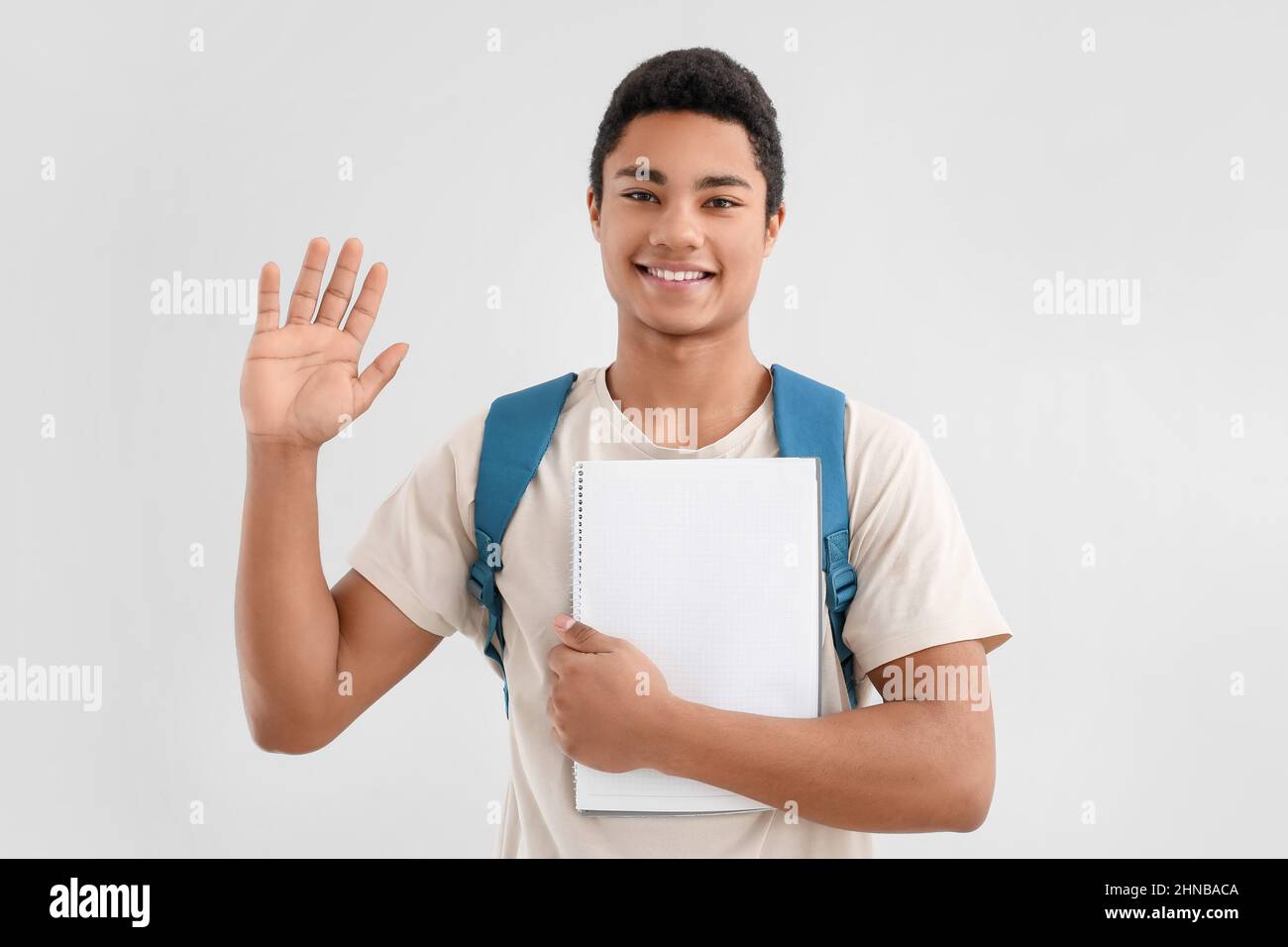 Male African-American student with notebook and backpack waving hand on ...