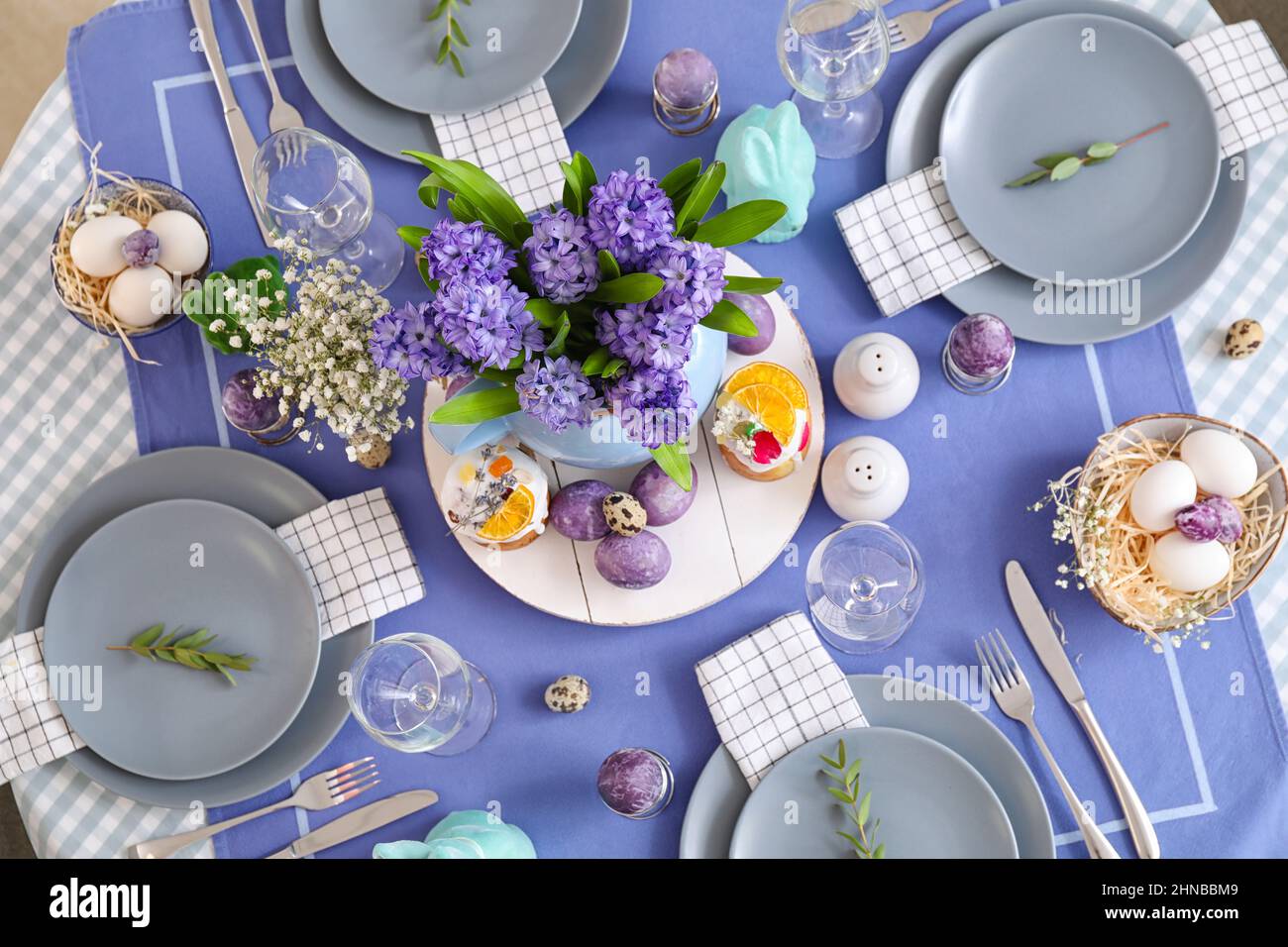 Vase with beautiful flowers, Easter cakes and eggs on served table Stock Photo
