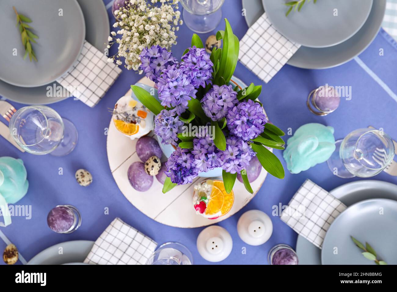 Vase with beautiful flowers, Easter cakes and eggs on served table Stock Photo