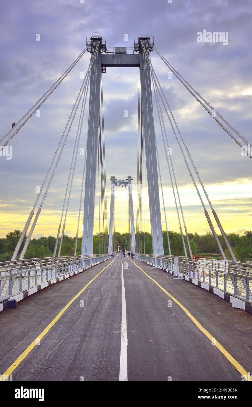 Supports and ropes of a pedestrian bridge under a cloudy sky. Siberia