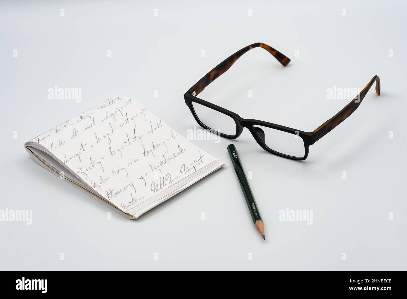 Notebook, glasses, green pencil and white background Stock Photo
