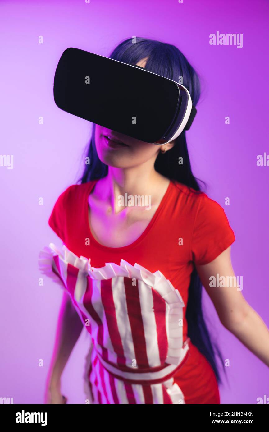 Woman in waitress costume is dancing while using Virtual Reality goggles - vertical. High quality photo Stock Photo