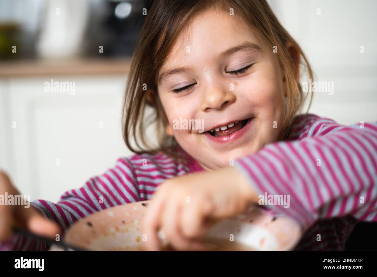 Close up of preschool girl portrait with funny expression eating soup