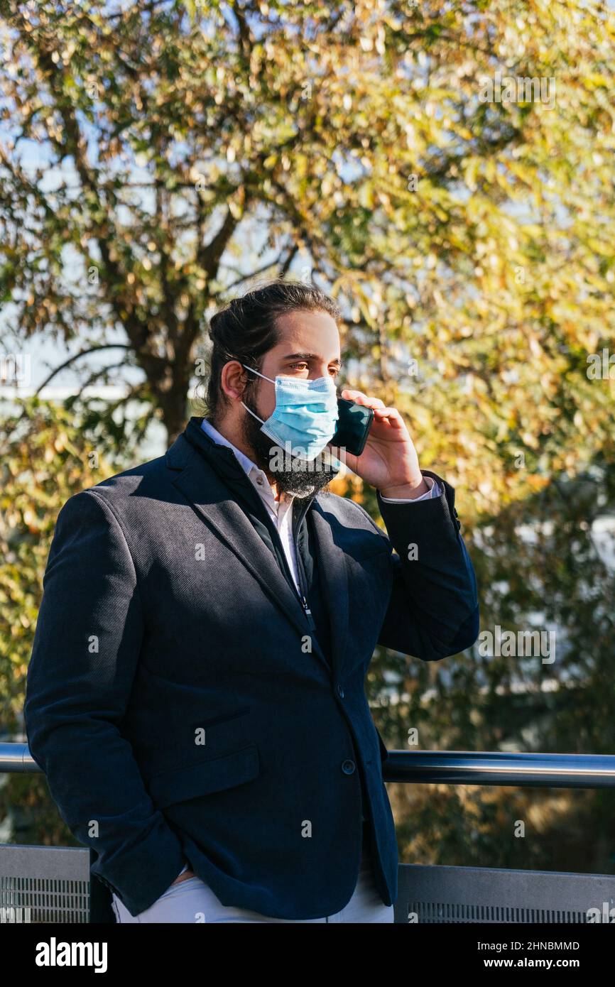 Young business man talking mobile with face mask Stock Photo