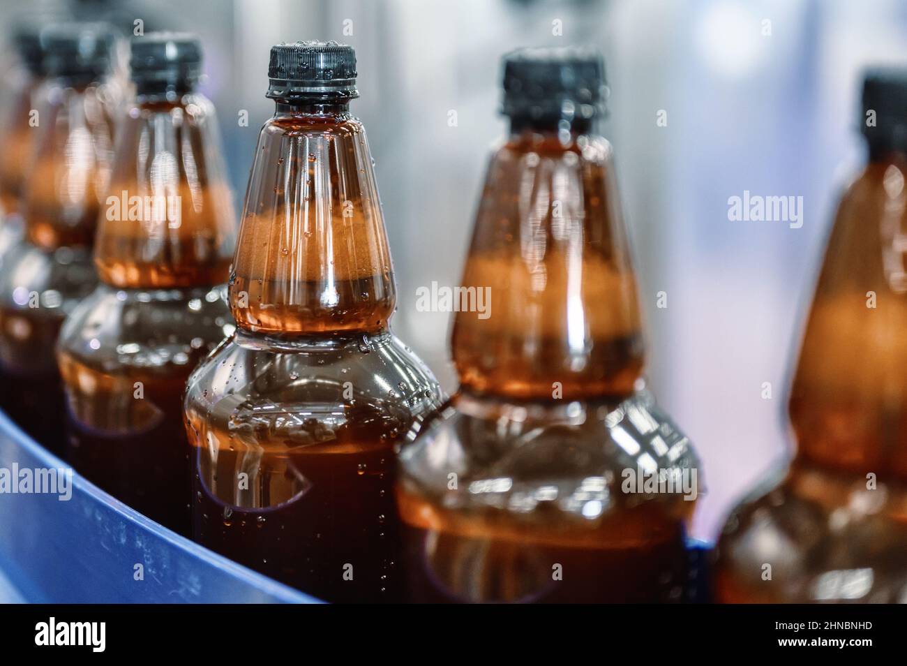 Plastic bottles with light filtered beer on the conveyor. Industrial
