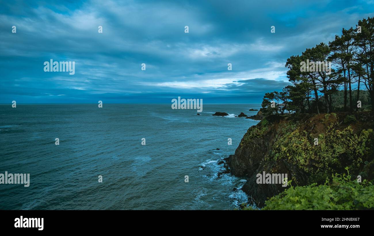 Landscape of the sea surrounded by cliffs and greenery under a cloudy ...