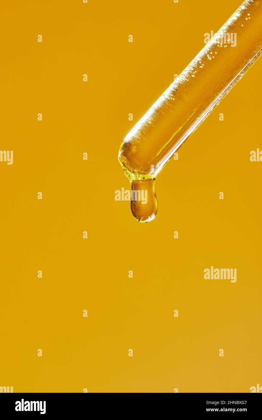 A drop of cosmetic aromatic oil drips from the pipette. Front view