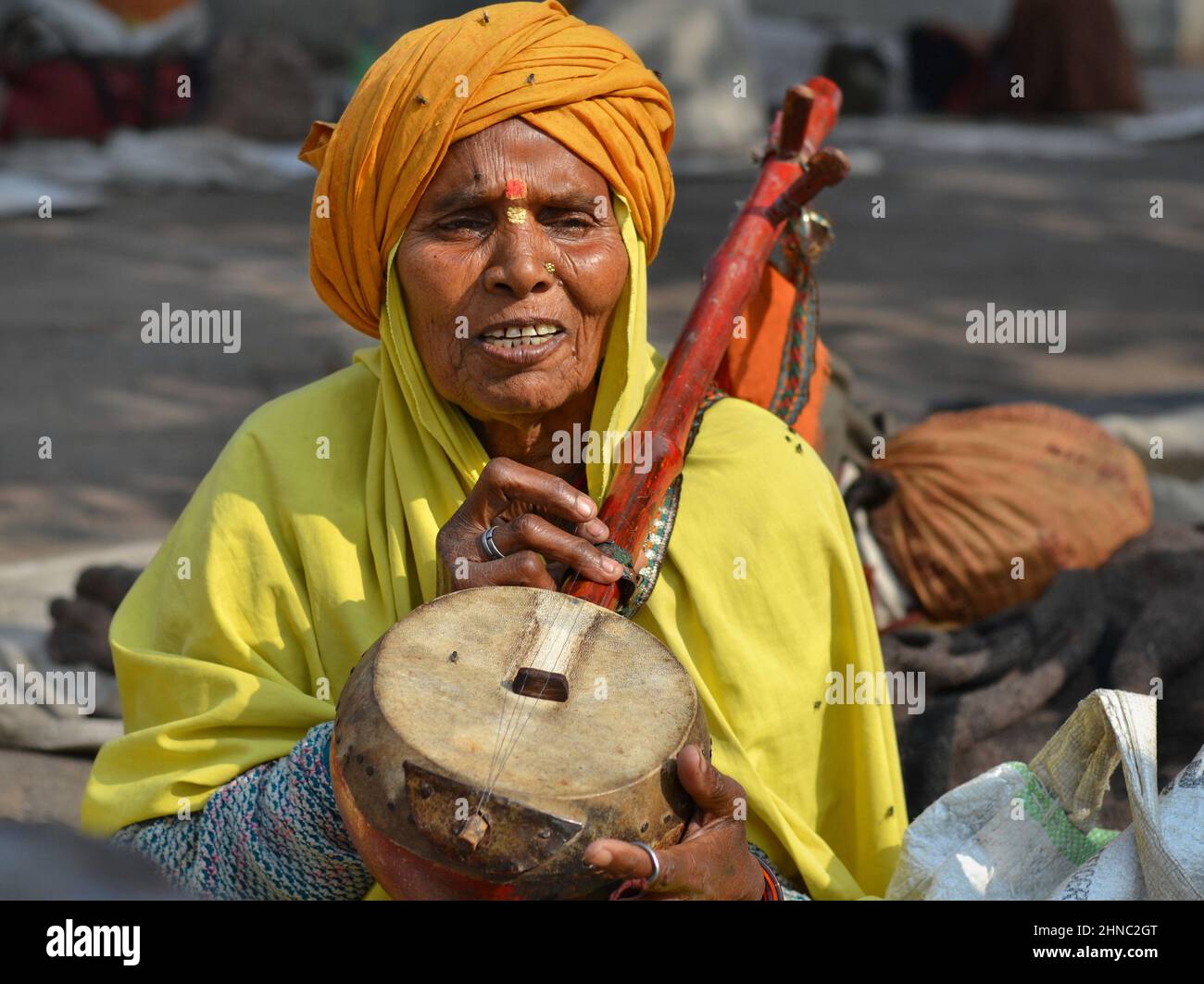 Old Indian temple musician with traditional dotar (plucked Indian string instrument) plays his instrument and sings at the Hindu Ram Raja Mandir. Stock Photo