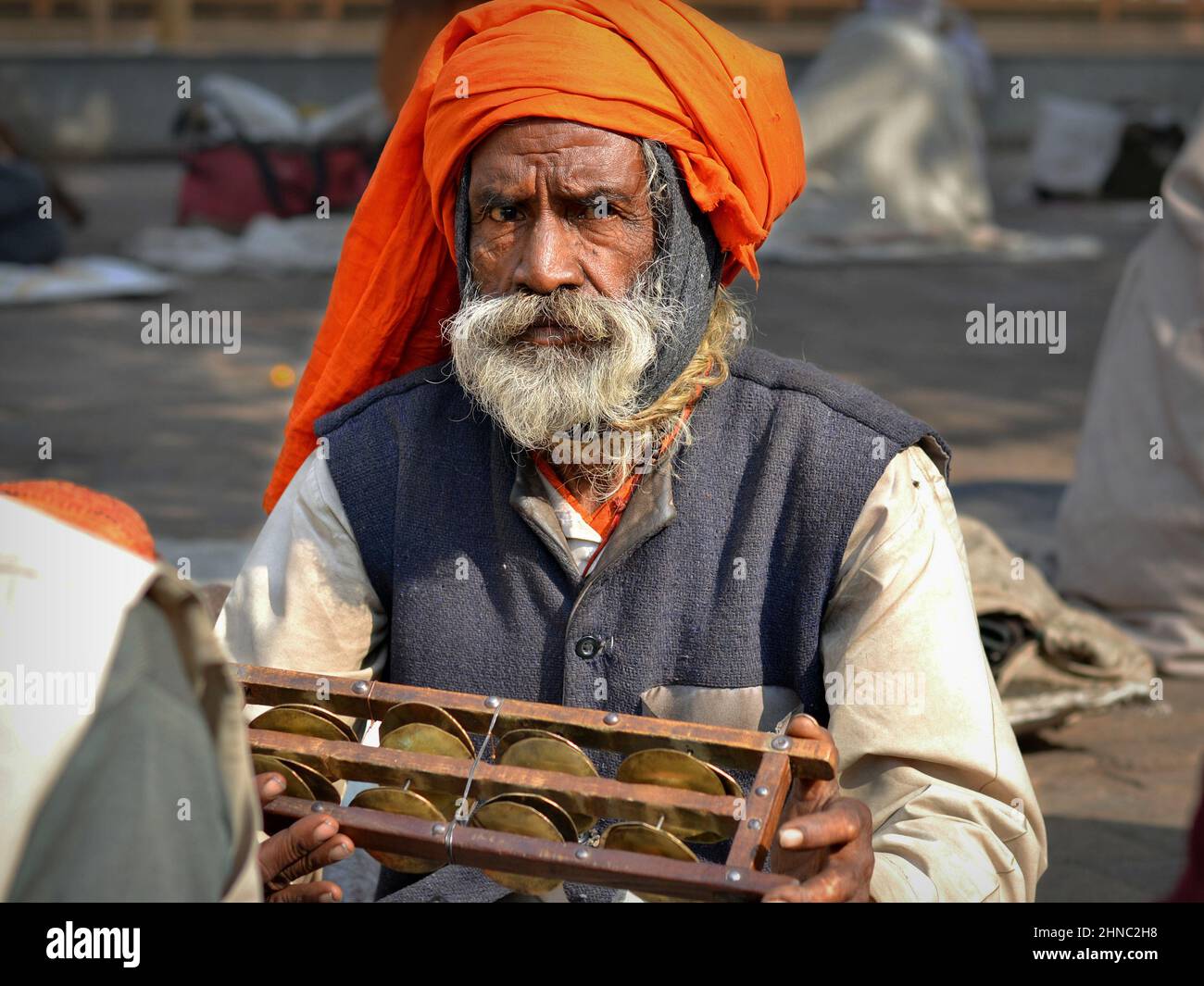 Old Indian temple musician with handmade jheeka (rectangular Indian tambourine) plays his instrument and sings at the Hindu Ram Raja Mandir temple. Stock Photo