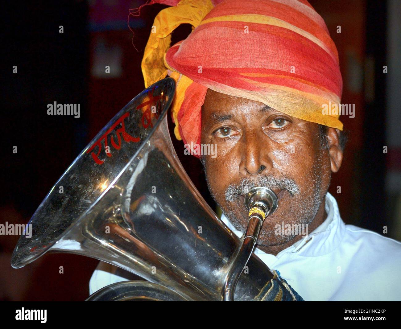 Elderly turbaned euphoniumist from a marching Indian British brass band plays his traditional euphonium musical instrument and looks at the camera. Stock Photo