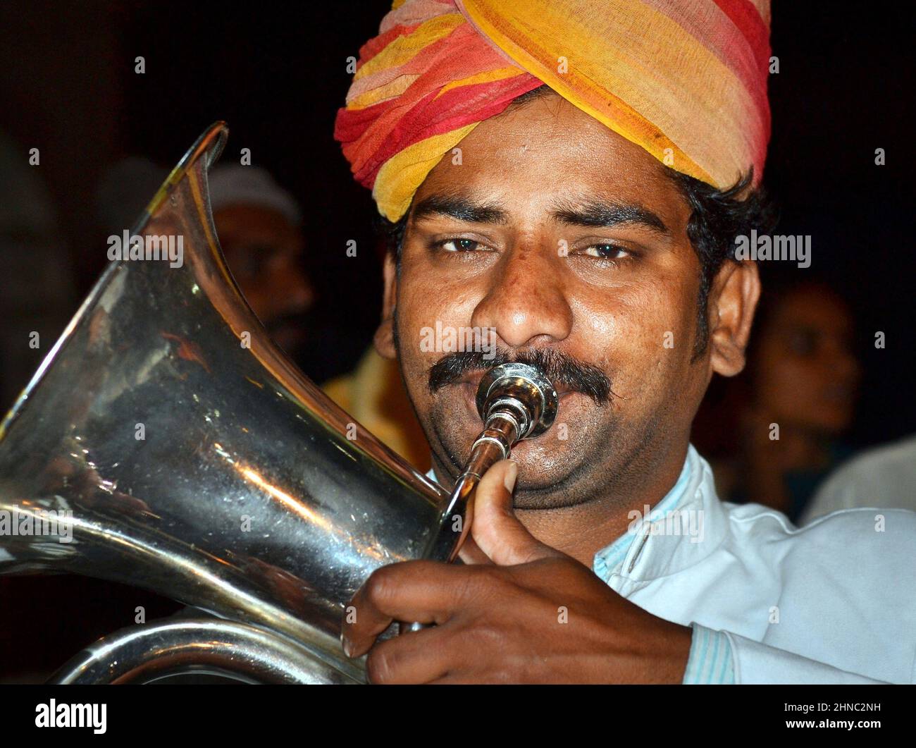 Young turbaned euphoniumist from a marching Indian British brass band plays his traditional euphonium musical instrument and looks at the viewer. Stock Photo