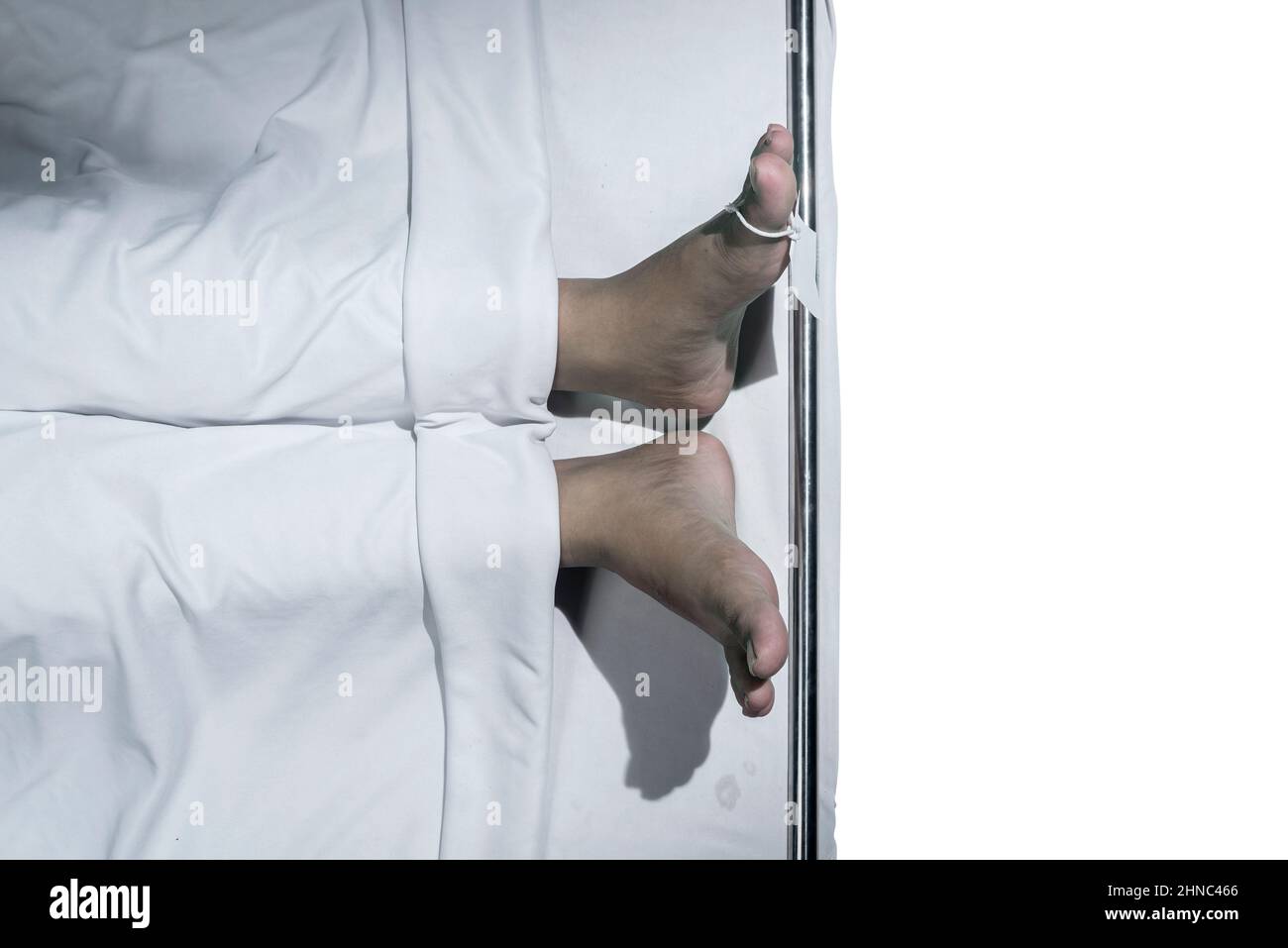 Human corpse covered with a sheet and name tag on the toe with white