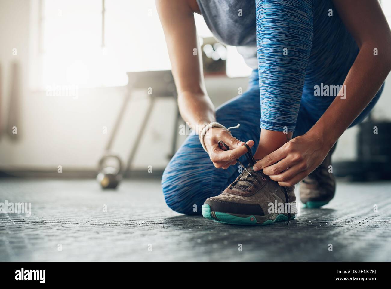 The right shoes makes all the difference. Shot of a woman tying her shoelaces in a gym. Stock Photo