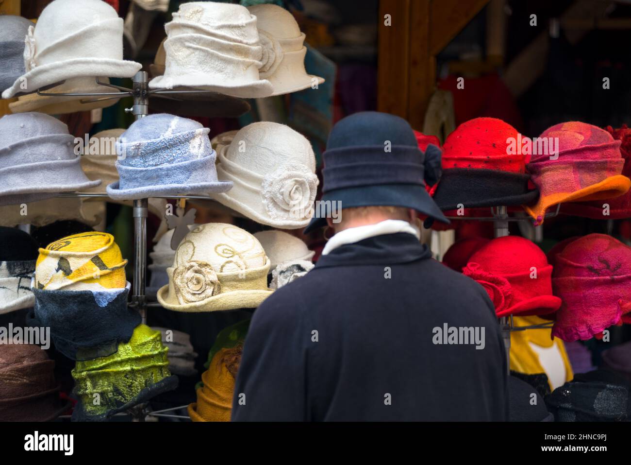 Woman in a felt hat examines the hats of the same style in a shop. Rear view Stock Photo