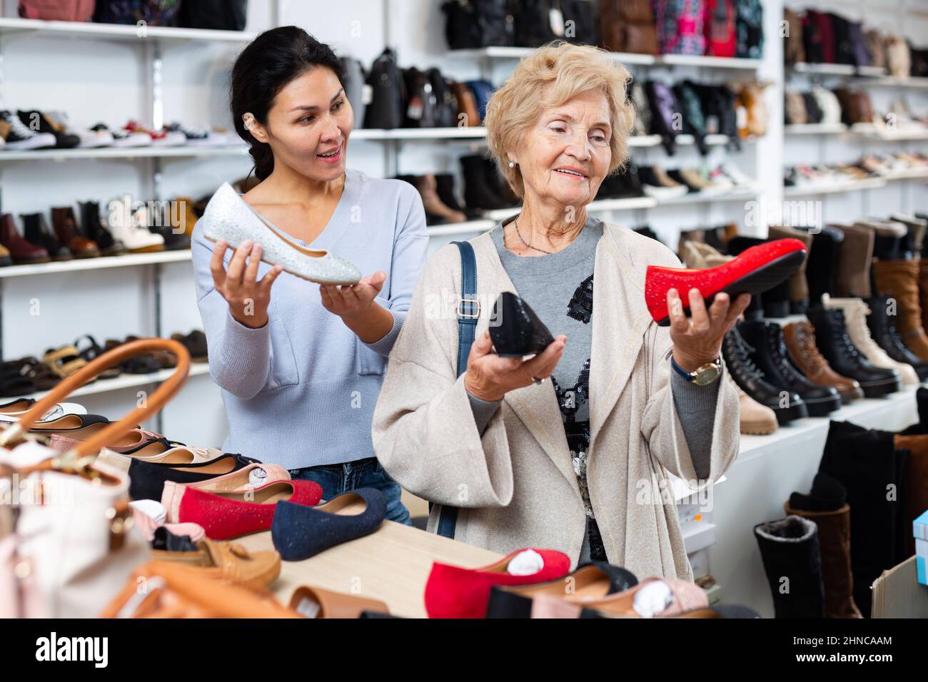 Consultant in helping old woman to choose footwear Stock Photo