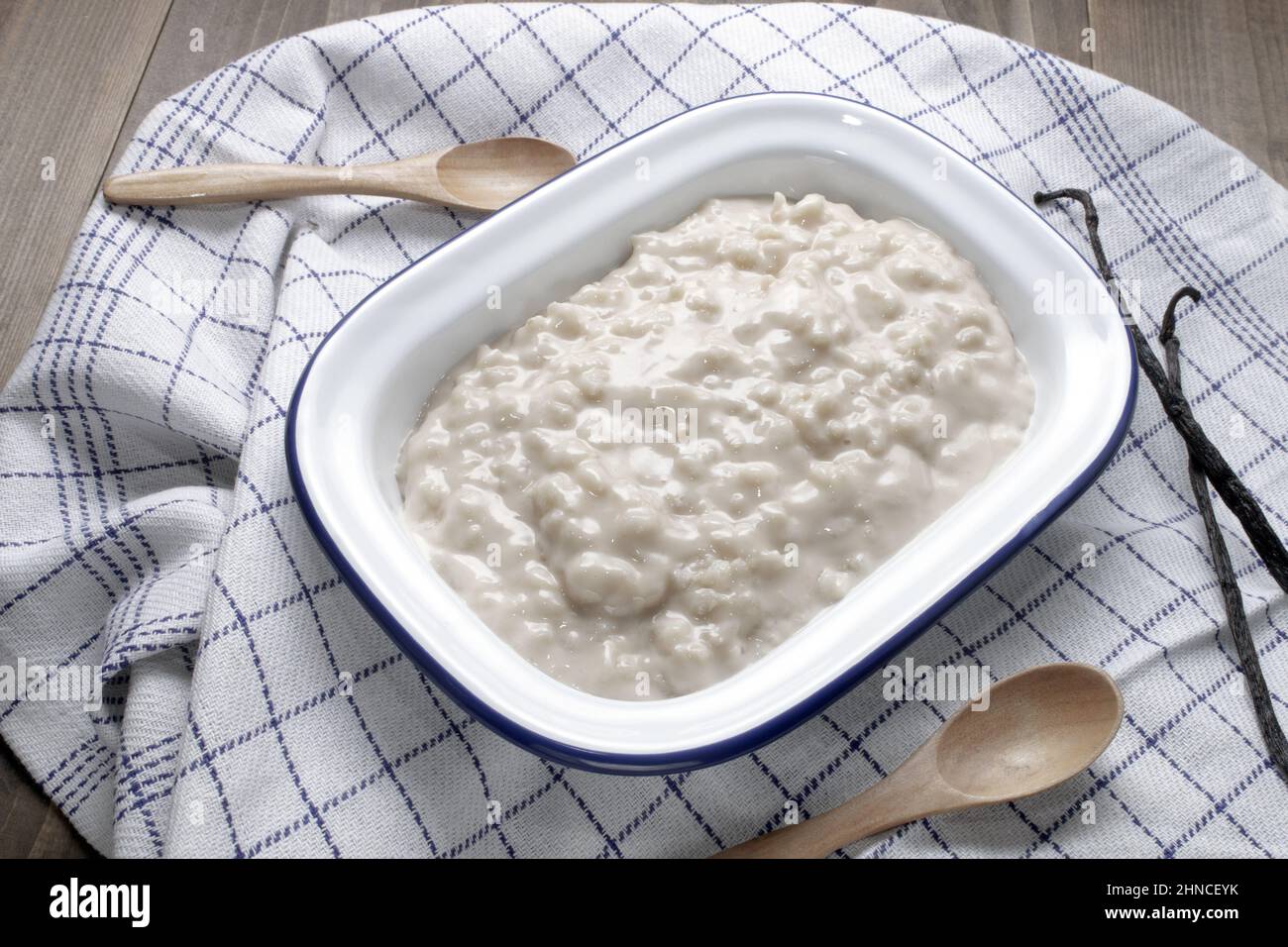 homemade vanilla rice pudding in a white enamel bowl and wooden spoons Stock Photo
