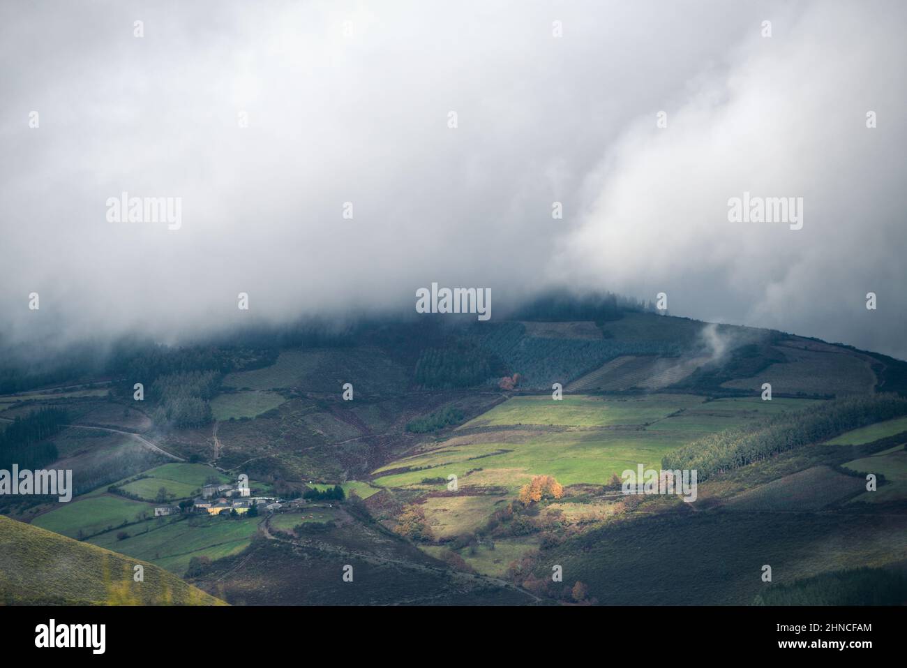 A small agricultural and livestock village at the foot of a cloud-covered mountain in Becerrea in Galicia Stock Photo