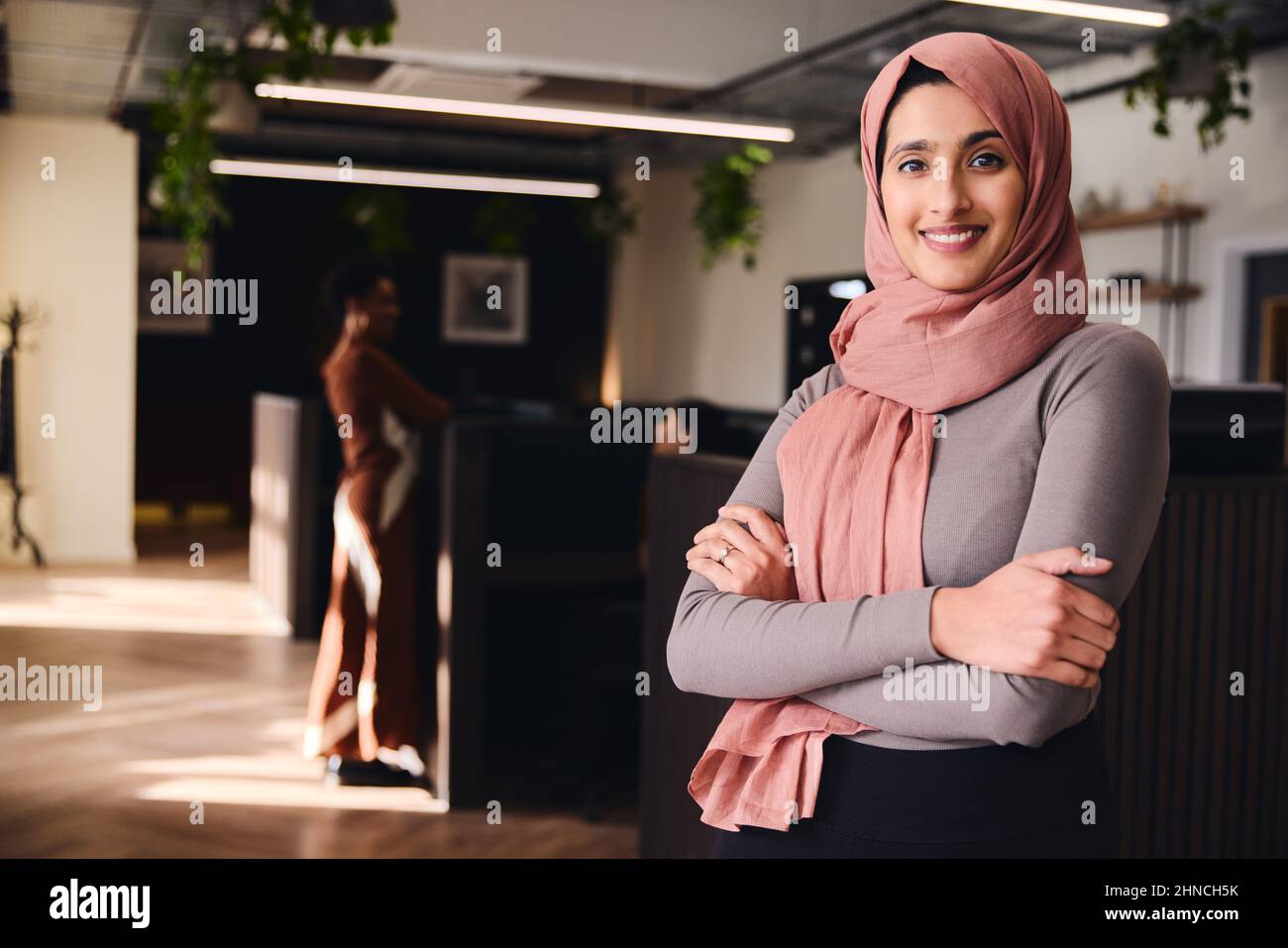 Portrait of confident young Middle Eastern woman smiling and looking at camera in coworking space Stock Photo