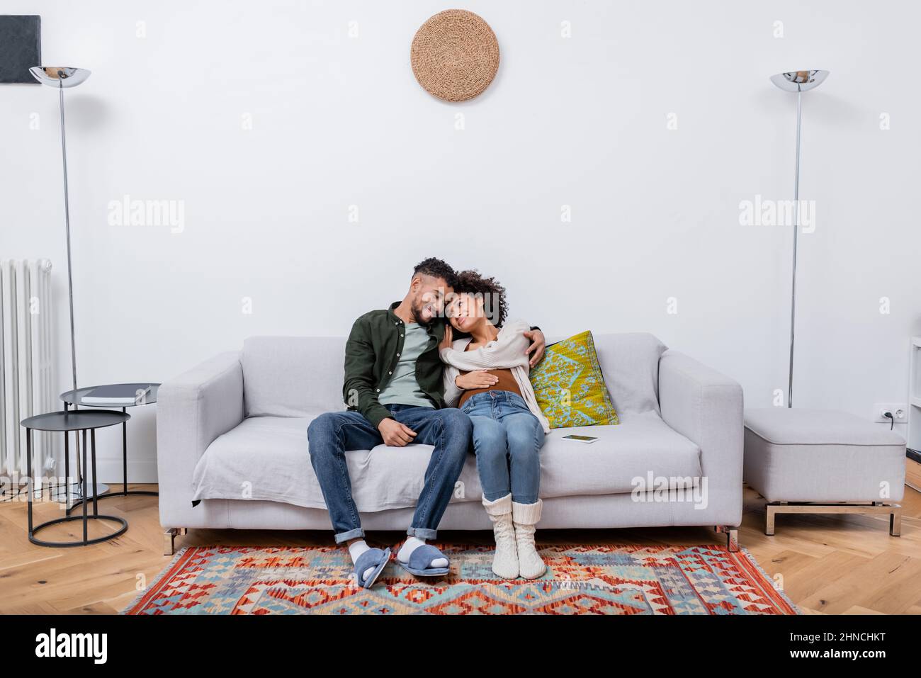 pregnant african american woman sitting with happy husband on couch in ...