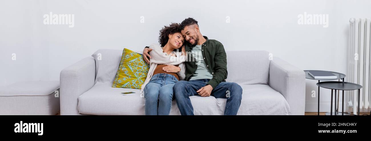 pregnant african american woman sitting with happy husband on couch in ...