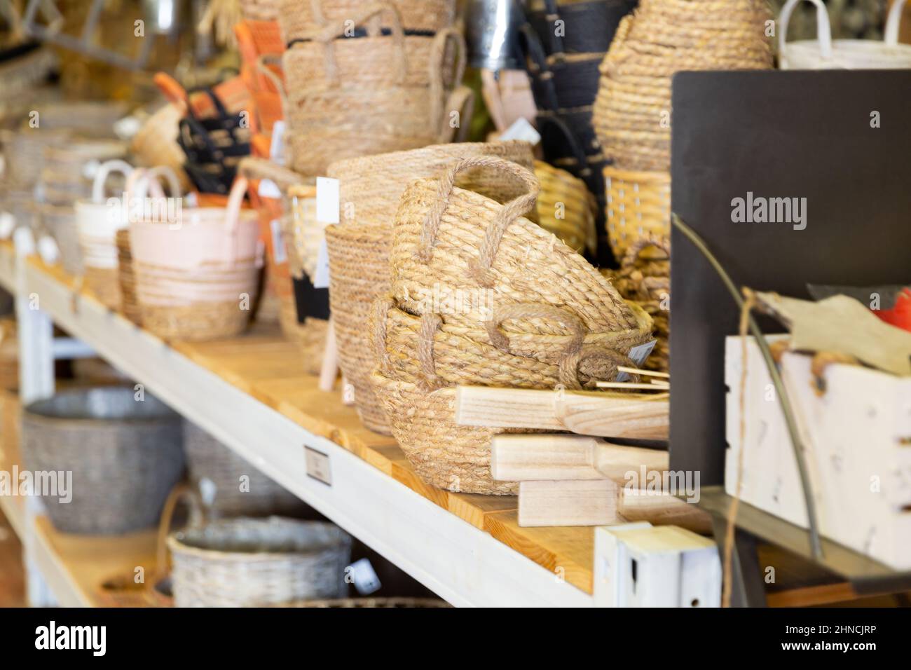 Wicker baskets and other handmade items on store shelves close up Stock