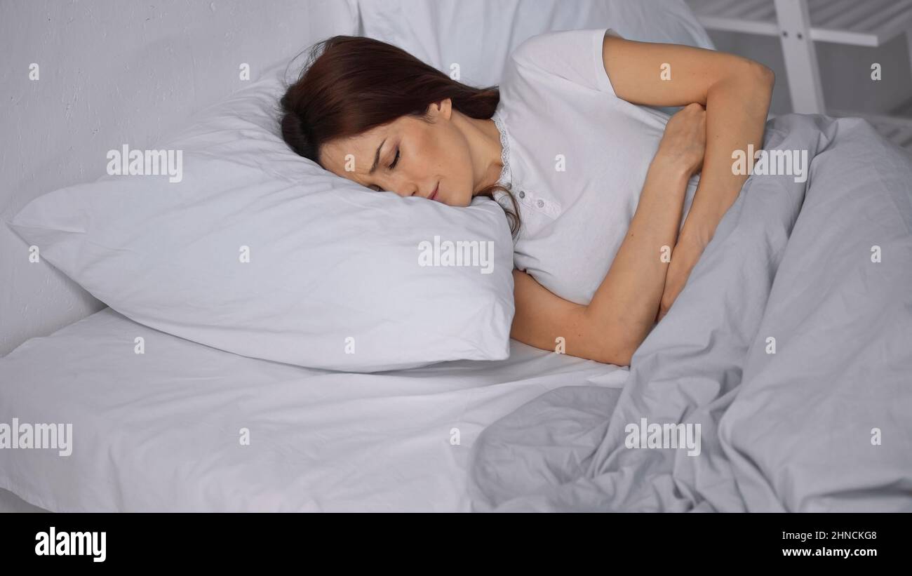 woman suffering from abdominal pain while lying in bed Stock Photo Alamy