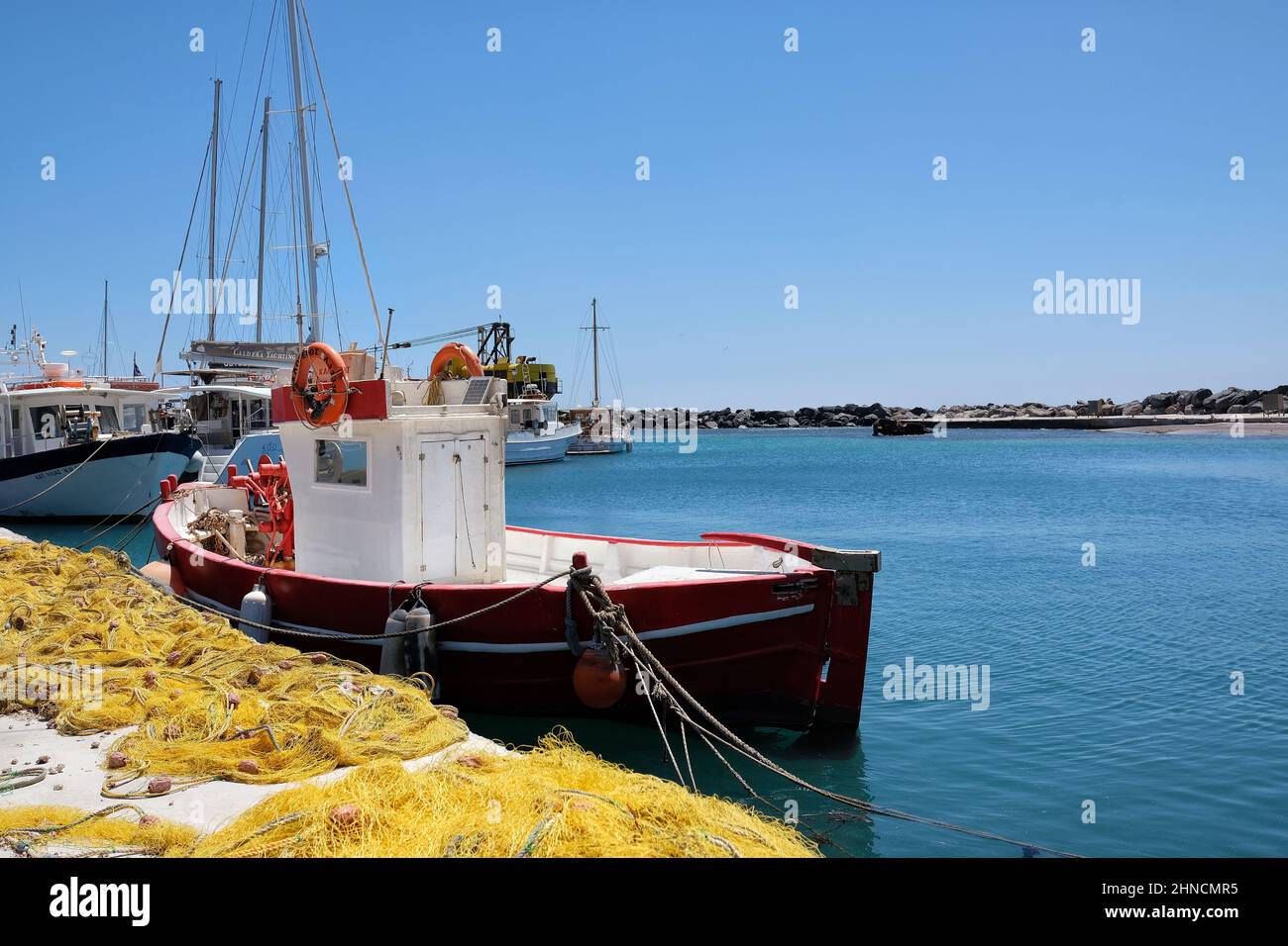 View of a fishboat and fishnets next to it at a small harbor in Santorini Greece Stock Photo
