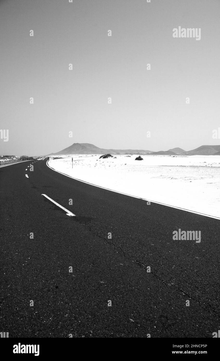 Lonely road in the desert. Black and white picture. including sand mountains and a single street. Stock Photo