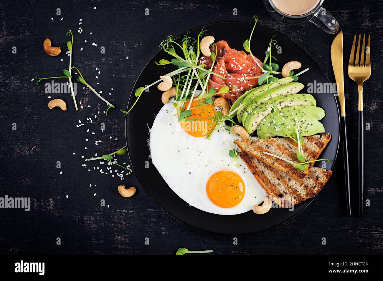Ketogenic diet breakfast. Fried eggs, salt salmon with microgreens, avocado, cashew nuts and
