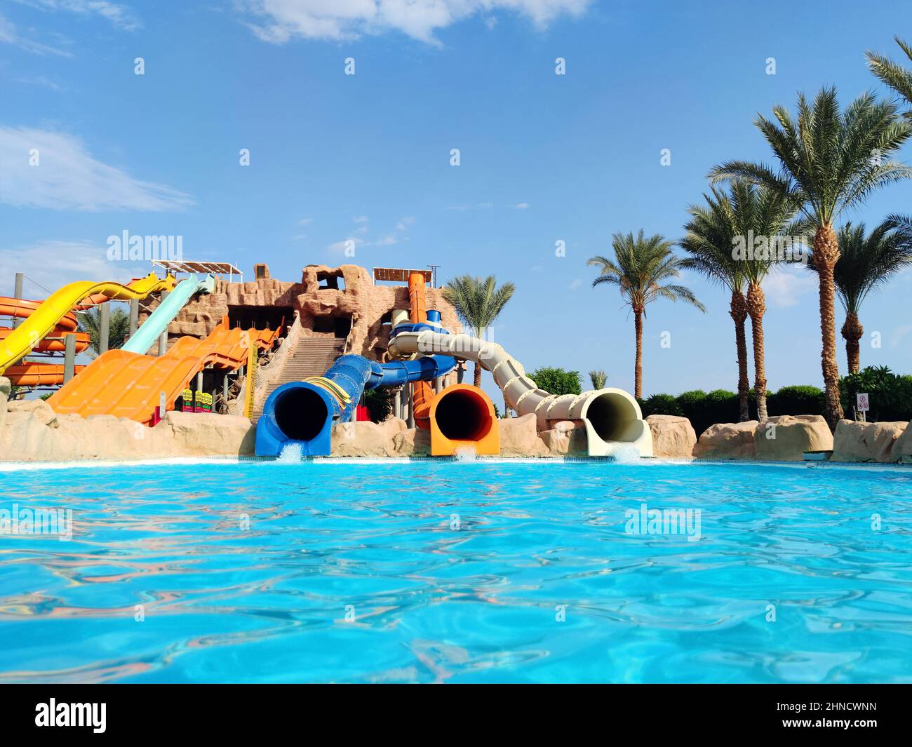 Water park with colorful slides and pools. Water slides and palm trees in a aqua park without people. Stock Photo