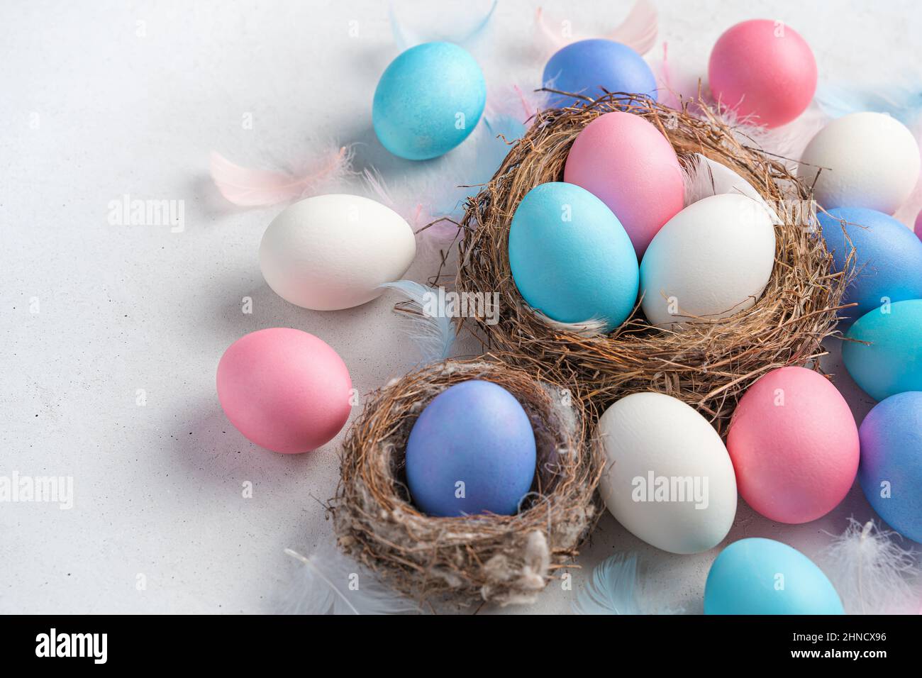Colored Easter eggs and nests on a gray background. Side view, copy space. Stock Photo
