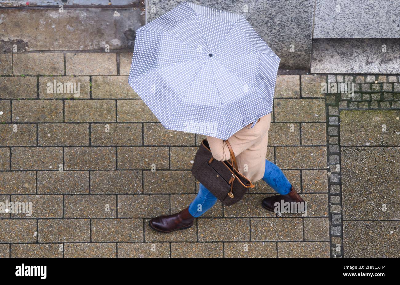 Hildesheim, Germany. 16th Feb, 2022. A woman walks through the city center with an umbrella. A powerful low-pressure system with gale-force winds of force 12 will pass over Lower Saxony and Bremen starting Thursday night, according to meteorologists. Credit: Julian Stratenschulte/dpa/Alamy Live News Stock Photo