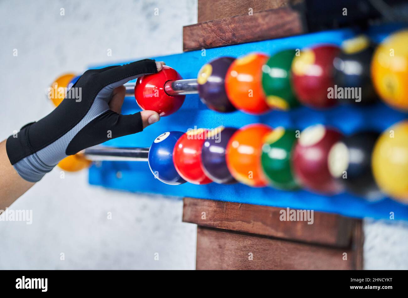 Hand of crop unrecognizable person in glove moving colorful ball on