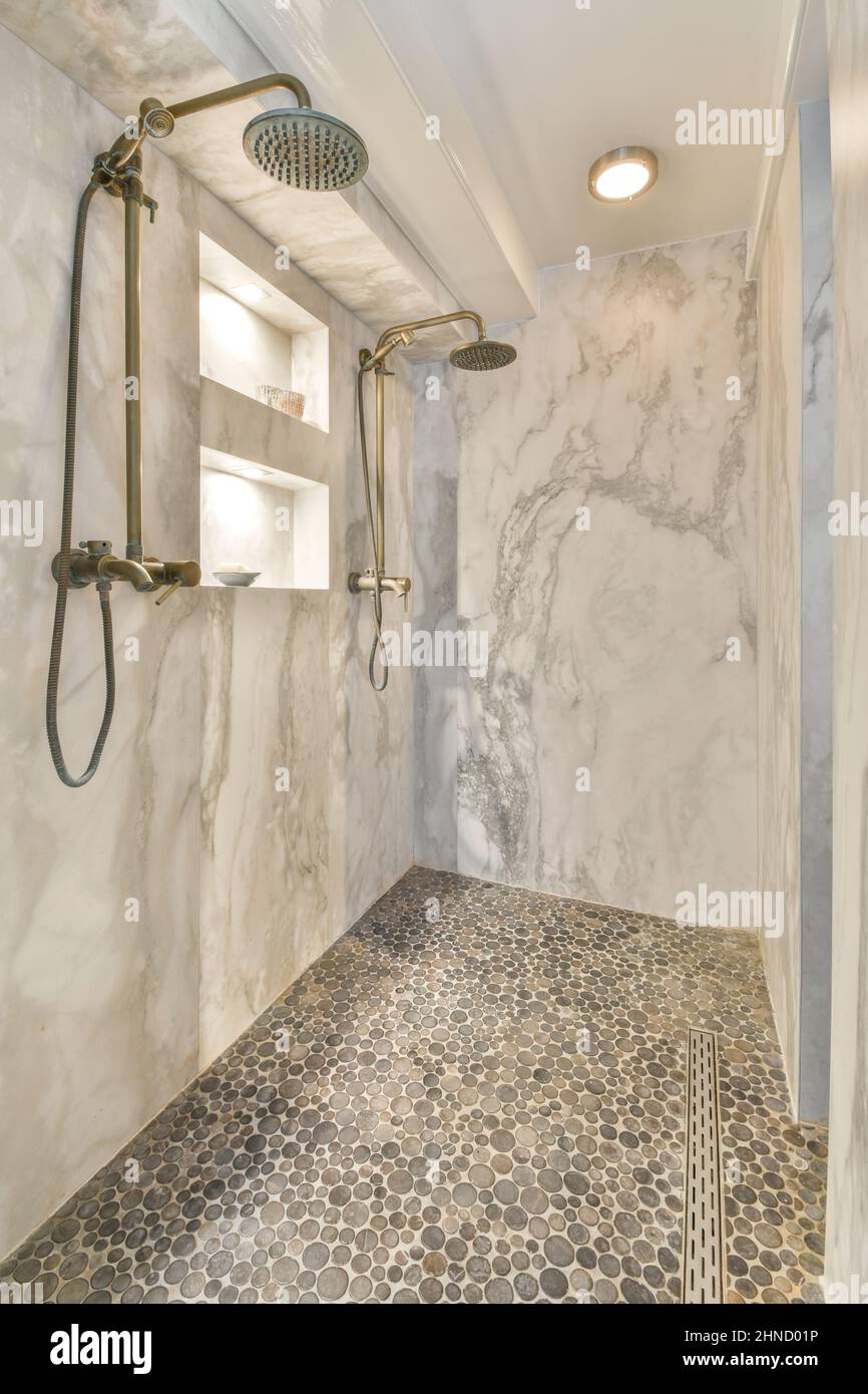 Shower hoses with heads attached to marble wall in light stylish