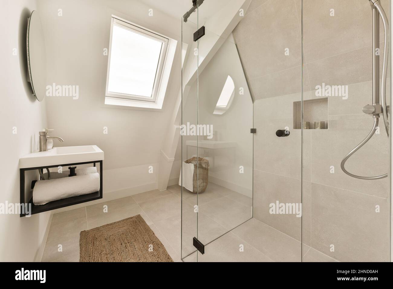 Interior of modern bathroom with shower washbasin under shelf with towel and glass shower cabin in house Stock Photo