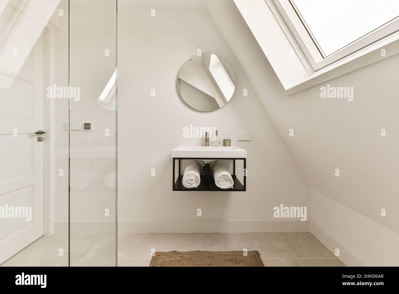 Interior of modern bathroom with shower washbasin under shelf with towel and glass shower cabin in house Stock Photo