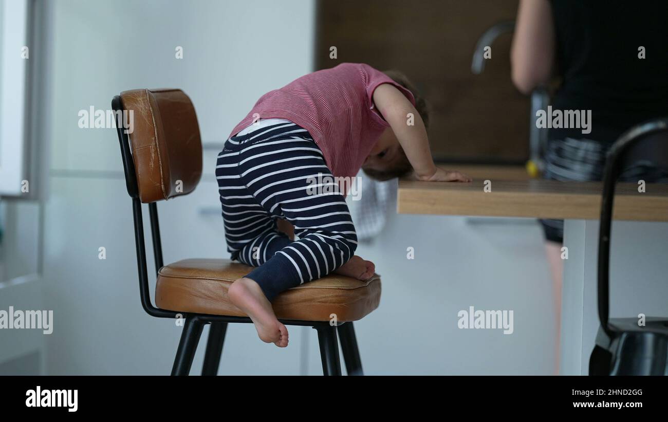 Child getting down from chair candid little boy steps down from high