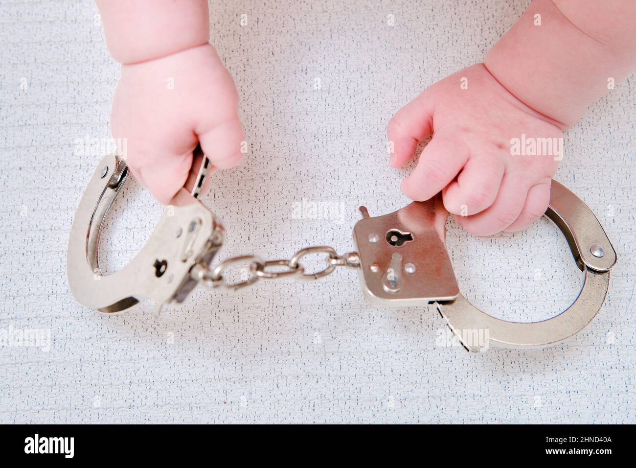 Baby hand and handcuffs, closeup. Children fingers and an object on a