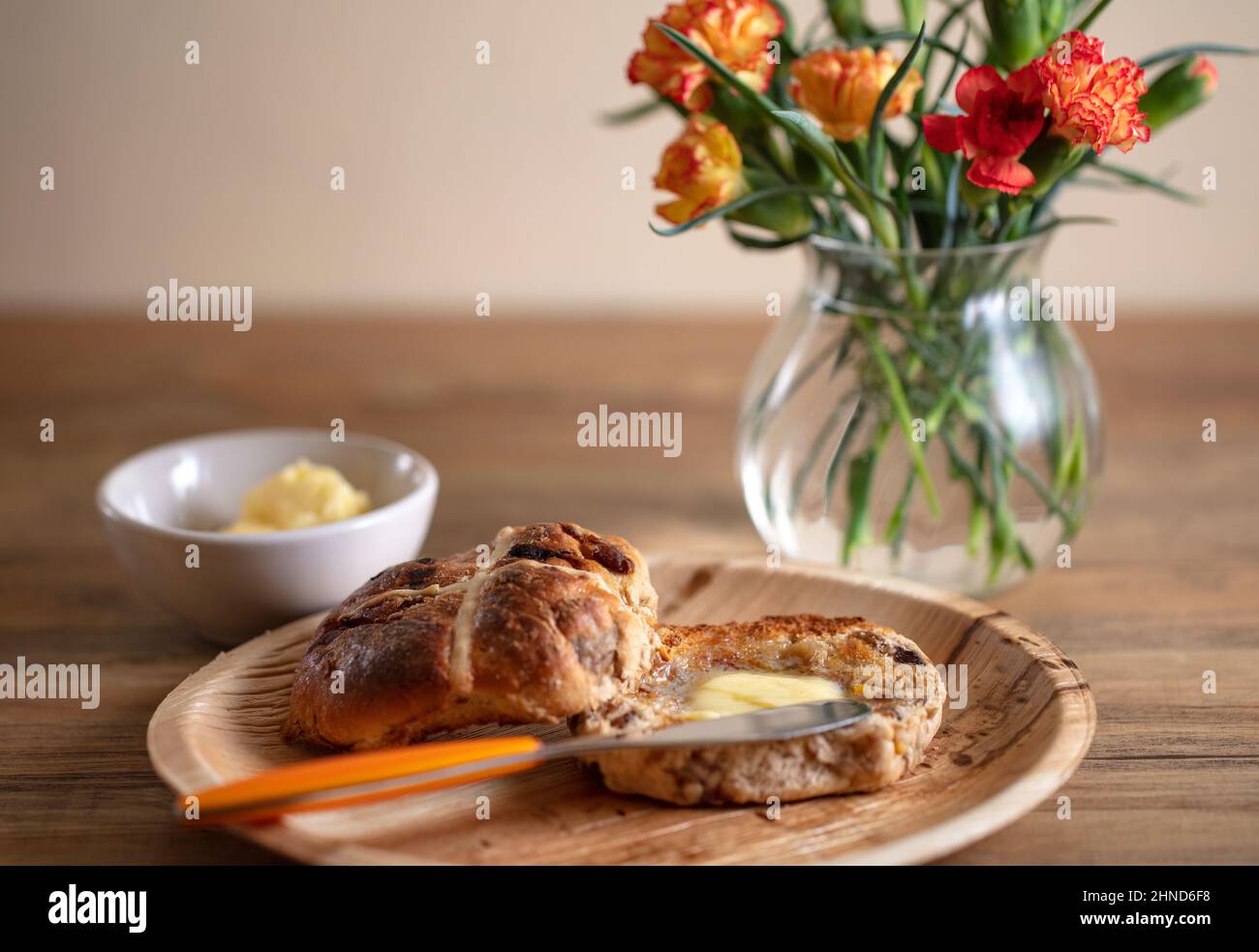 A toasted and buttered Hot Cross Bun, a sweet spiced bun traditionally